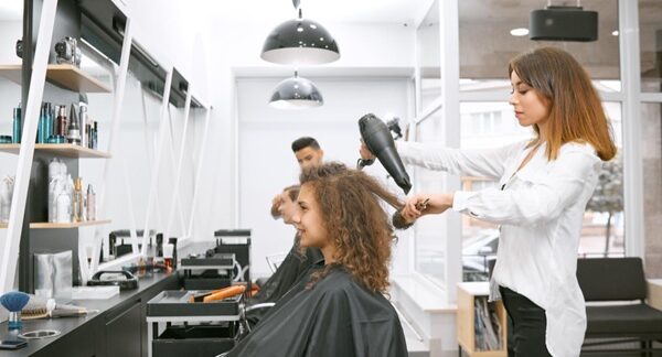 Peluqueros - Mujer en un salón de belleza siento atendida por uno de los mejores peluqueros en Madrid