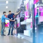 Tiendas de electrodomésticos - Vendedor de una de las mejores tiendas de electrodomésticos en Madrid atiendo a un hombre que busca aparatos eléctricos y utensilios del hogar