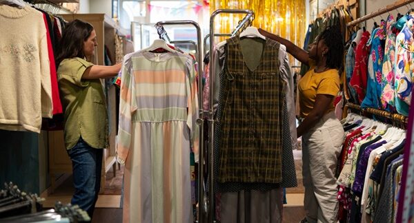 Tiendas de ropa vintage - Personas observando ropa de segunda mano para comprar ropa vintage en una de las mejores tiendas vintage de Madrid