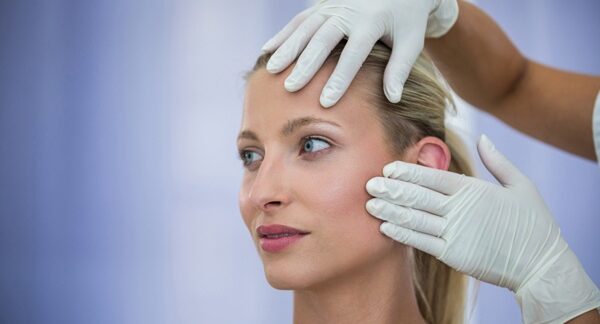 Clínicas de lifting facial - Médico estético evaluando el rostro de una mujer para realizar un tratamiento de rejuvenecimiento facial en la mejor clínica estética Madrid