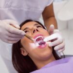 Periodoncistas - Dentista especialista en encías realizando un tratamiento periodontal a una mujer en la mejor clínica dental de Madrid